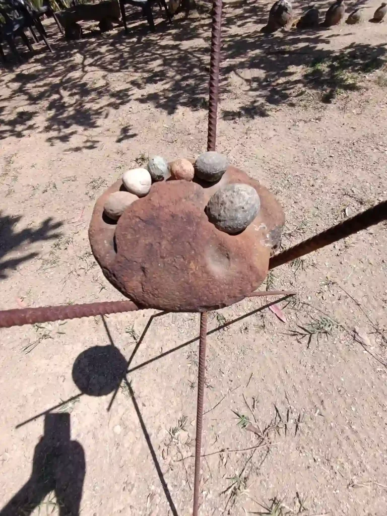 Estructura rústica de metal oxidado con piedras sobre tierra, parte del entorno natural en Cabaña El Oteo, Villa de Leyva.