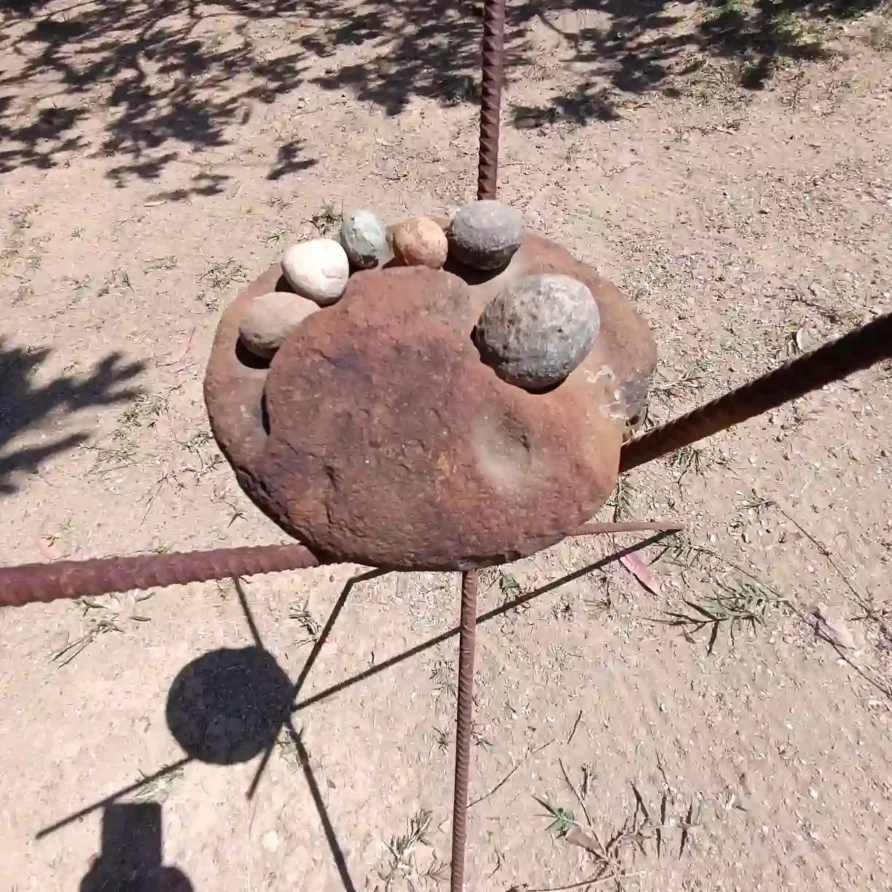 Estructura rústica de metal oxidado con piedras sobre tierra, parte del entorno natural en Cabaña El Oteo, Villa de Leyva.