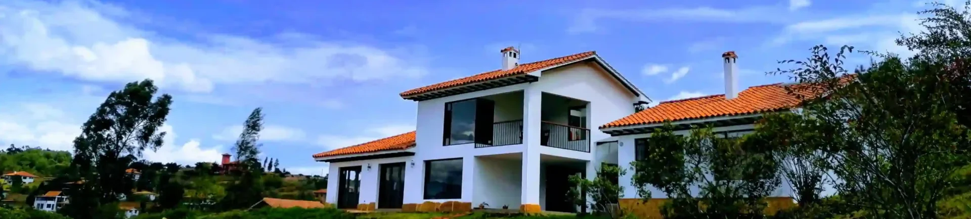 Hermosa casa hichatana de alquiler vacacional en Zipaquirá con tejado naranja y camino de ladrillo bajo cielo azul.