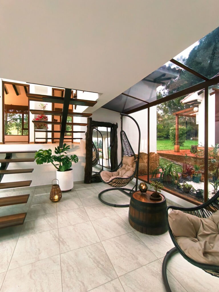 Interior de casa hichatana con sillas colgantes y vistas al jardín.