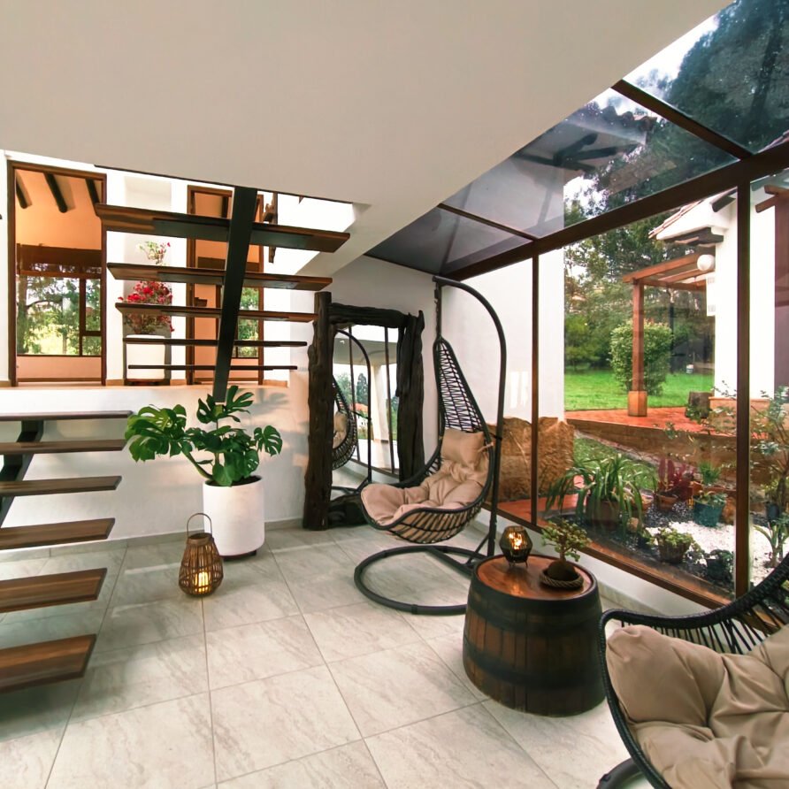 Interior de casa hichatana con sillas colgantes y vistas al jardín.