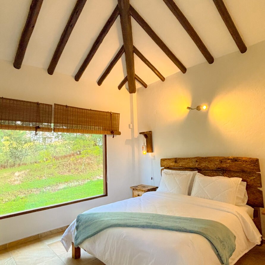 Habitación rústica con cama de madera y vistas a la naturaleza.